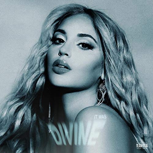 A close-up portrait of Alina Baraz with long wavy hair, in cool blue tones.