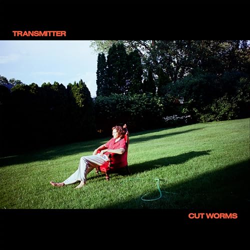 Album cover: person sitting in a red chair on a green lawn.