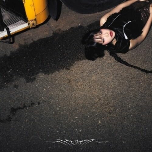 CD cover: Woman with dark hair lying near a yellow vehicle.