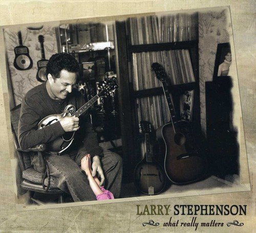 Larry Stephenson holding a mandolin, with guitars and a child nearby.