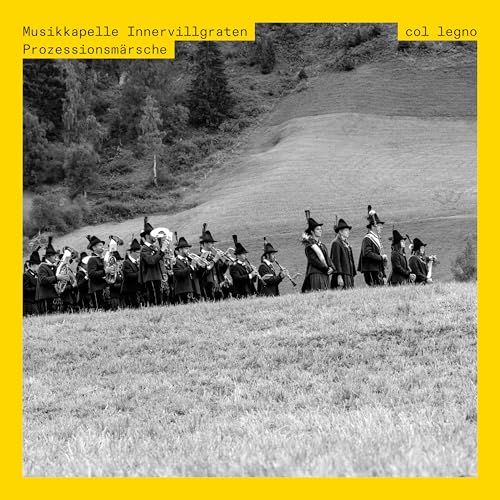 Black and white photo of a brass band marching across a grassy field.