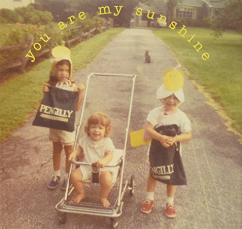 Vintage photo of two young girls and a baby in a stroller on a road.
