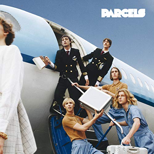 Band members in pilot and stewardess uniforms stand by an airplane.
