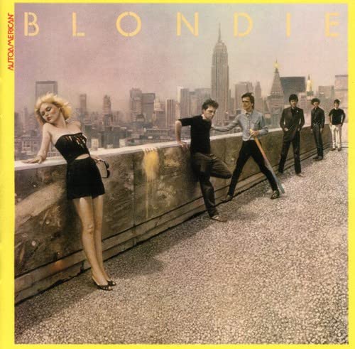 Blondie band members stand on a rooftop with the New York City skyline behind.