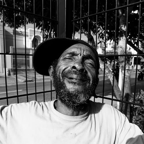 Black and white portrait of a smiling man with a beard and cap.