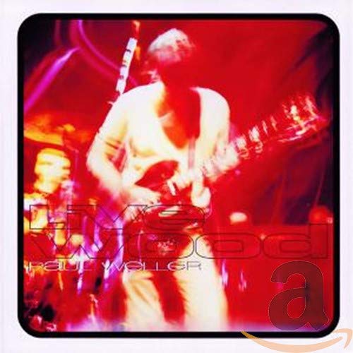 Paul Weller playing guitar onstage, bathed in red and purple light.