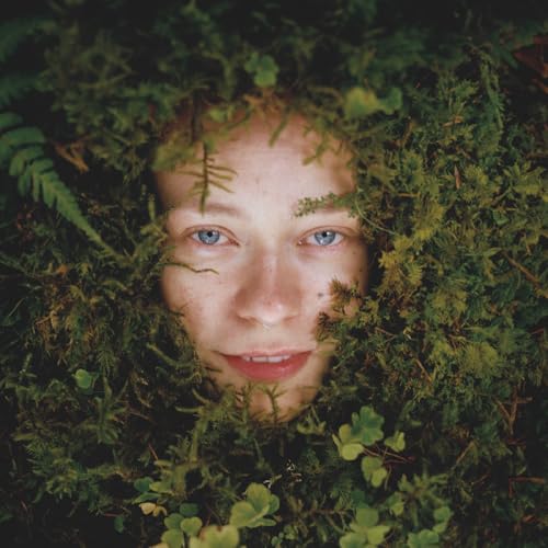 Woman’s face partially obscured by lush green foliage.