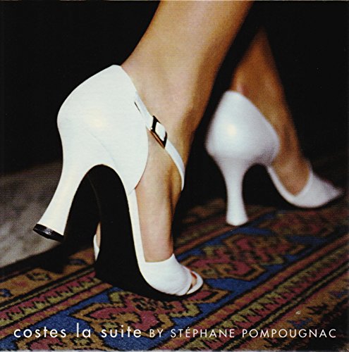 Close-up of white high-heeled shoes on a patterned rug.