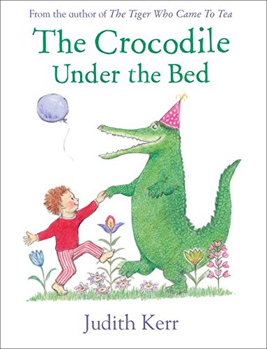A child in pajamas holds hands with a green crocodile wearing a party hat.