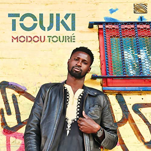 CD cover for Modou Toure’s “Touki” featuring a man in front of graffiti.