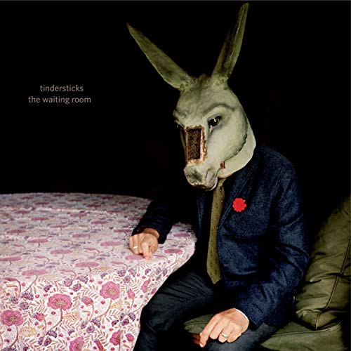 Person in a donkey mask wearing a suit, seated at a table.