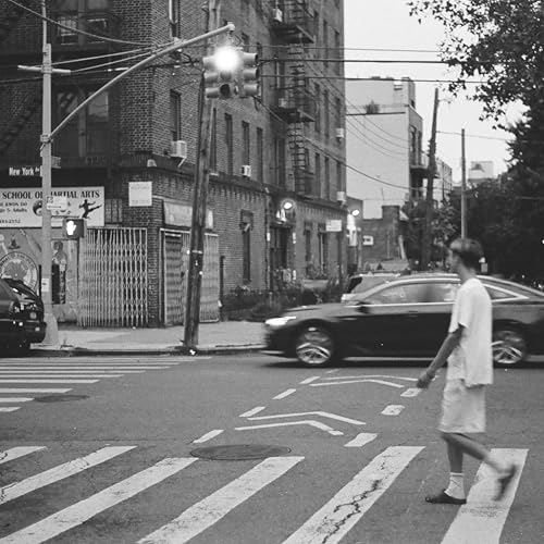 Black and white street scene with a person crossing a road.