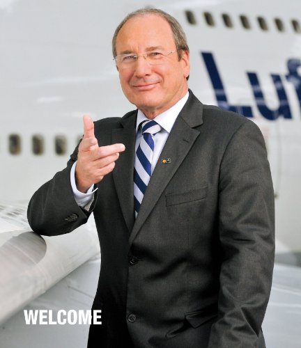 Man in suit pointing, airplane wing and "Welcome" text visible.