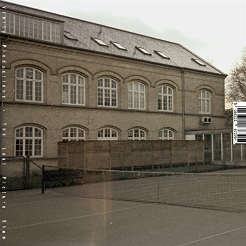 Brick building with many windows, a fence, and a tennis net.