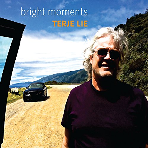 CD cover: Man with sunglasses, car on a rural road, mountains.