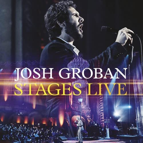 Josh Groban singing into a microphone on a concert stage.