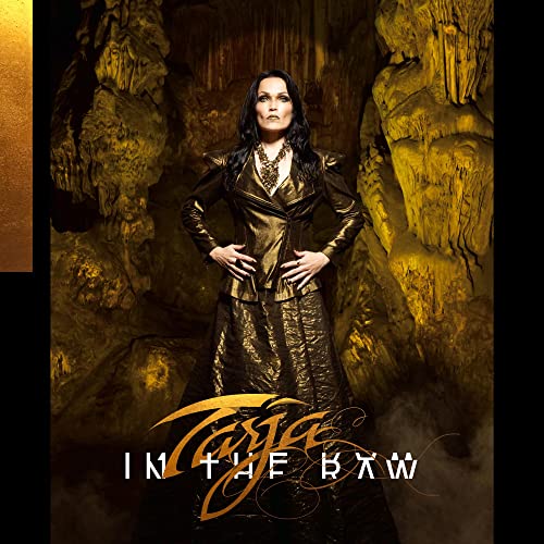 Tarja Turunen stands in a golden cave wearing a metallic jacket and long skirt.
