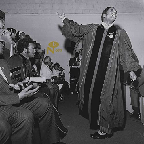 Black and white photo of a pastor with raised hands, preaching.