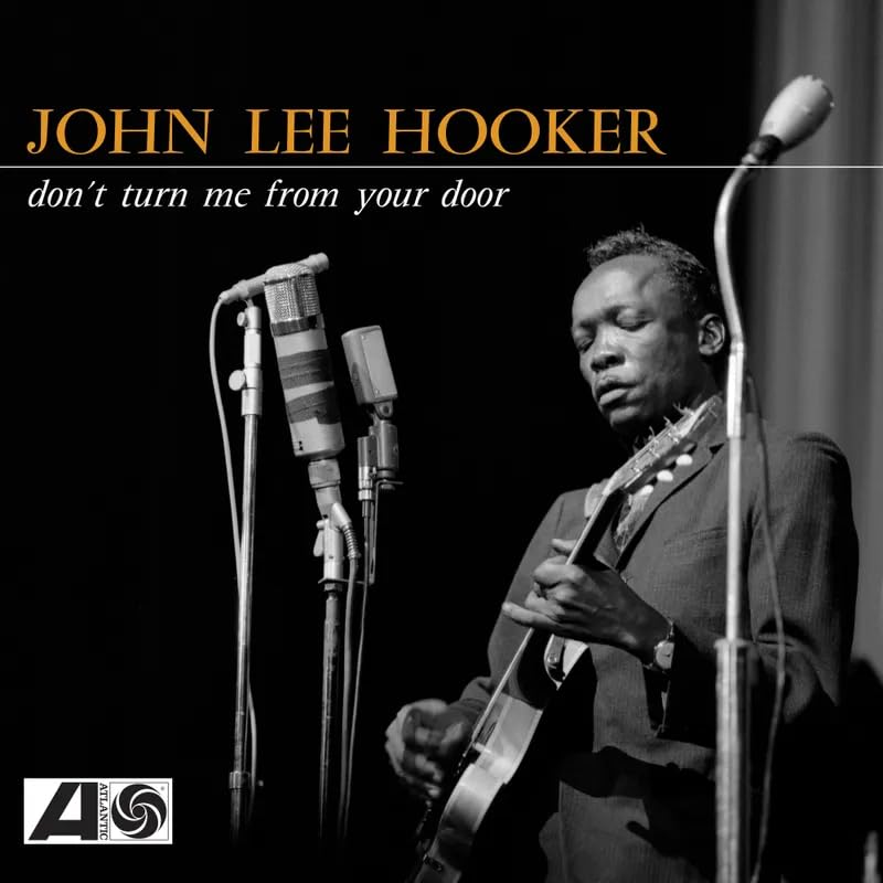Black and white portrait of John Lee Hooker with a microphone and guitar.
