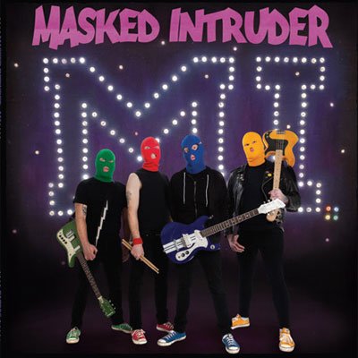 Four masked musicians with guitars stand before illuminated letters "M.I.