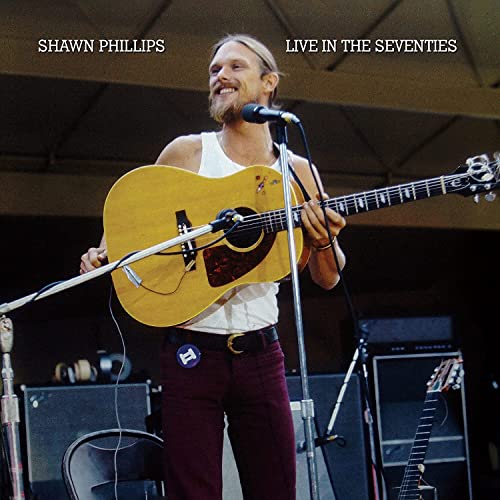 Shawn Phillips playing acoustic guitar on stage, album cover.