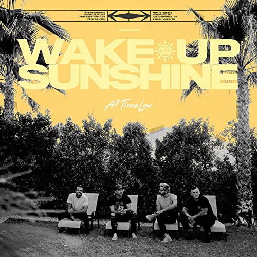 Four band members sit on lounge chairs in front of trees against a yellow background.
