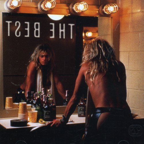 Man with long blonde hair looking at his reflection in a mirror.