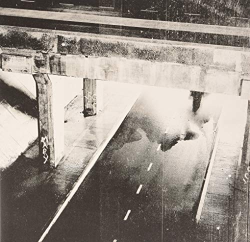 Black and white photo of a concrete bridge overpass above a road.