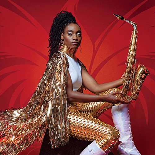 Lakecia Benjamin posing in a gold outfit and neckpiece holding a saxophone against red.