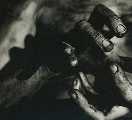 Black and white photo of hands reaching, shadowed, textured surface.
