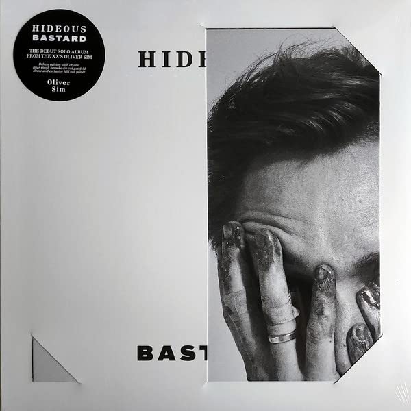 Black and white vinyl record cover featuring a fragmented portrait of Oliver Sim.