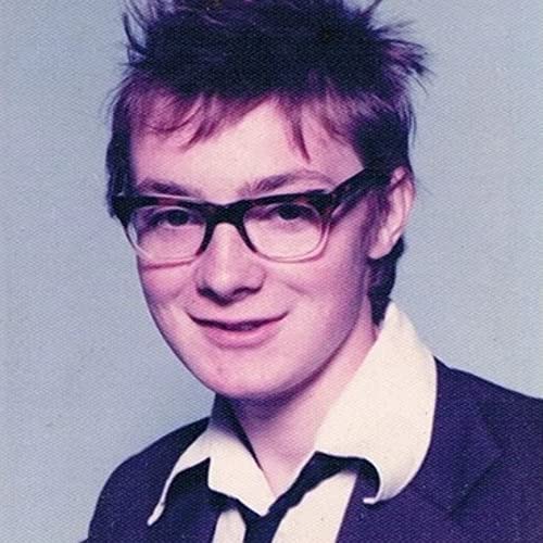 Close-up portrait of Terry Edwards with spiky hair and black-rimmed glasses.