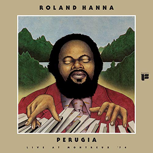 Roland Hanna portrait playing piano, mountains in background, album cover art.