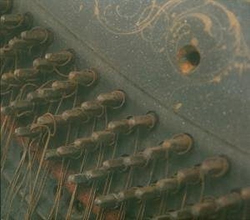 Close-up of rusted metal pins and swirling patterns on a dark surface.