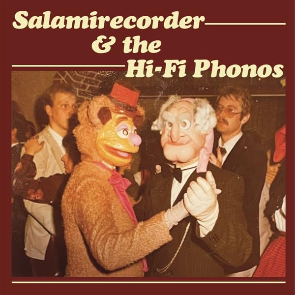 Vinyl record cover featuring musicians and costumed characters in a group photo.