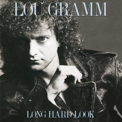 Black and white portrait of Lou Gramm with curly hair and a leather jacket.
