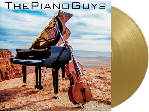 Grand piano and cello on a desert cliff with a gold vinyl record disc.