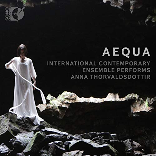 Woman in white dress stands on rocks, album cover for “aequa”.
