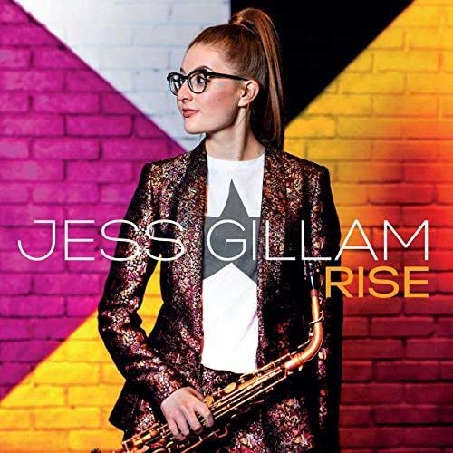 Jess Gillam poses with a saxophone, album title “Rise” overlaid on a brick wall.