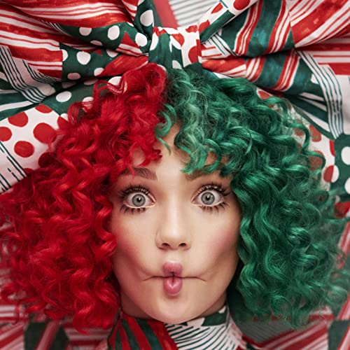 Sia with split red and green curly hair, looking at the viewer.