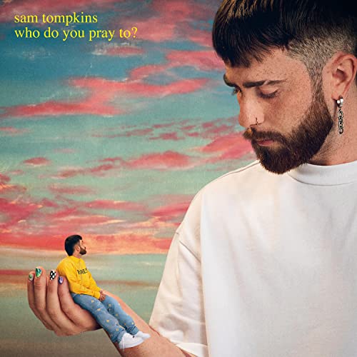 Man with beard looks down at miniature self against colorful sky.