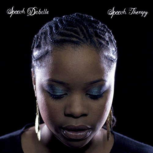 Close-up portrait of Speech Debelle with braided hair and teal eyeshadow.