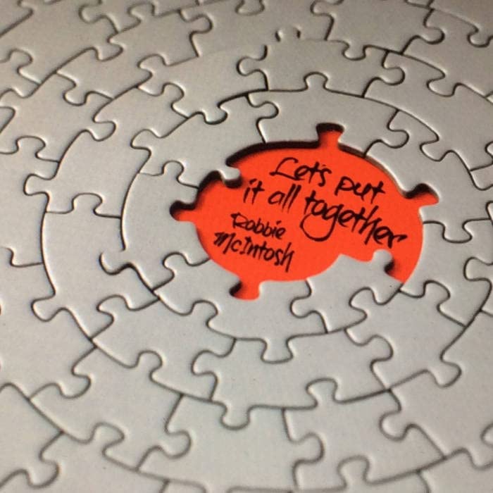 Jigsaw puzzle with a red piece displaying "Robbie Mcintosh - Let's Put It All Together.