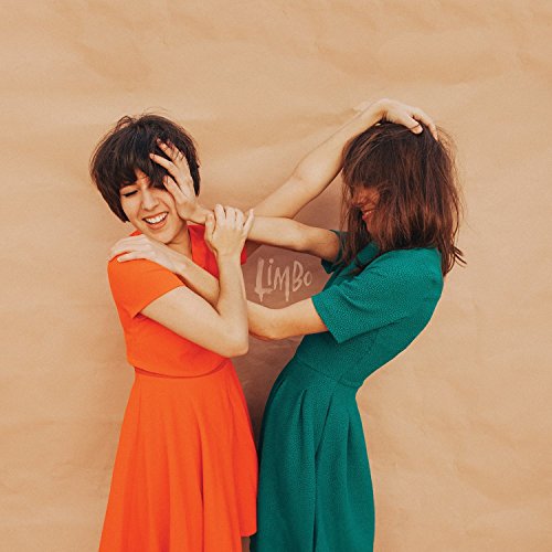 Two women in colorful dresses playfully reach for each other’s faces.
