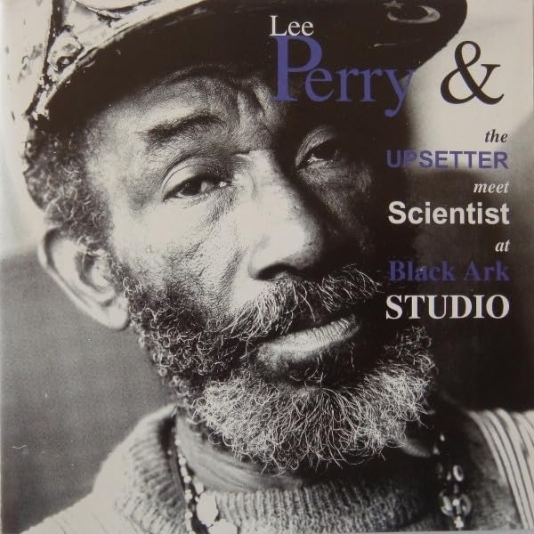 Black and white close-up portrait of Lee Perry wearing a hat and necklace.