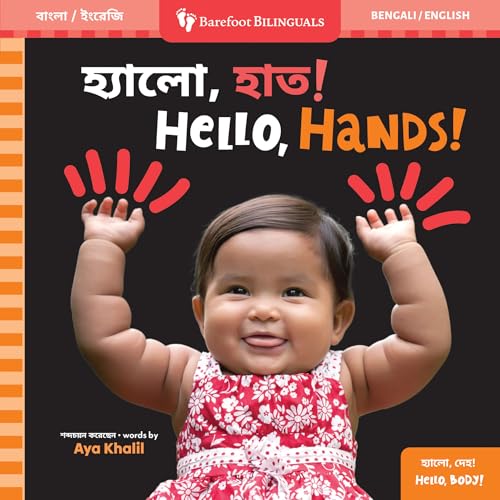 A smiling baby in a floral dress raises both hands against a black background.