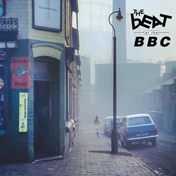 CD cover: street scene with a person running, vintage cars, and fog.