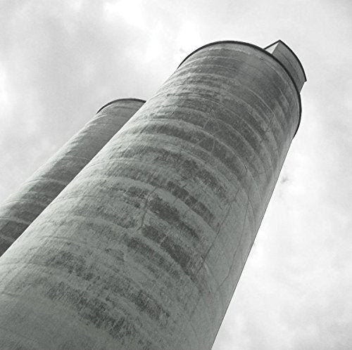Black and white photo of tall, cylindrical concrete towers against sky.