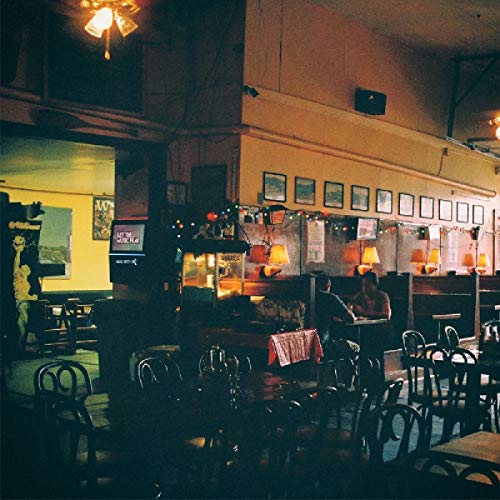 Dimly lit bar interior with tables, chairs, and framed pictures.