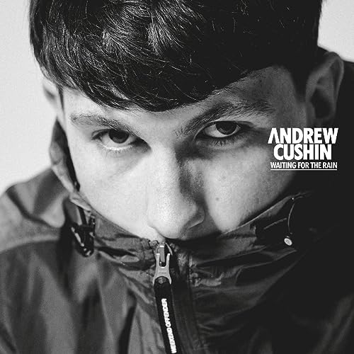 Black and white portrait of Andrew Cushin wearing a hooded jacket.